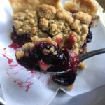 a forkful of cherry crumb crunch pie with the slice in the background