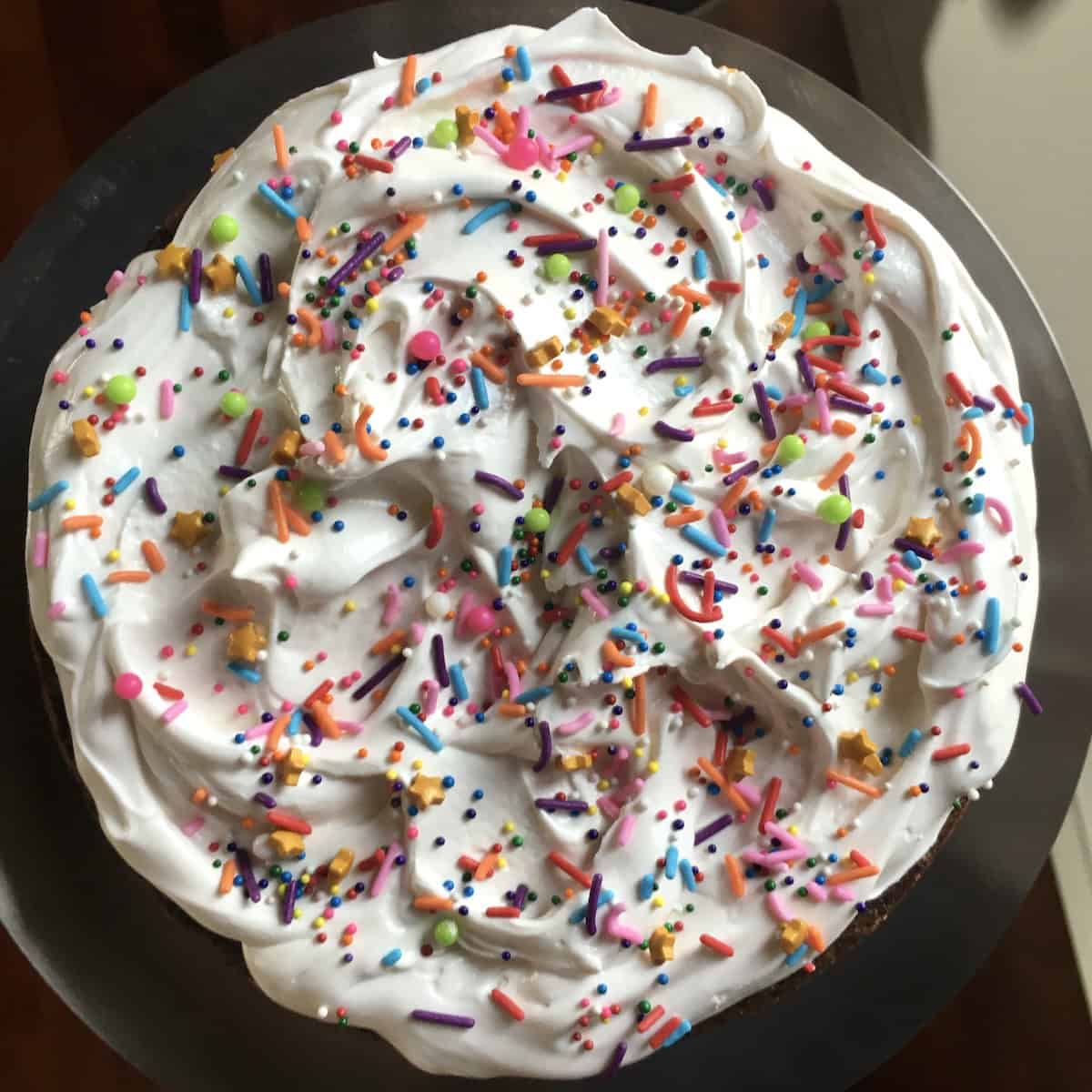 Top down view of classic devil's food cake with fluffy 7-minute frosting and colorful sprinkles, traditional devil's food cake recipe showing the best frosting for this moist devil chocolate cake.
