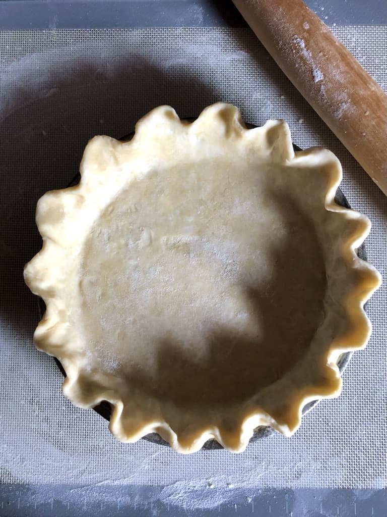 lard and butter pie dough in glass pie plate ready to bake