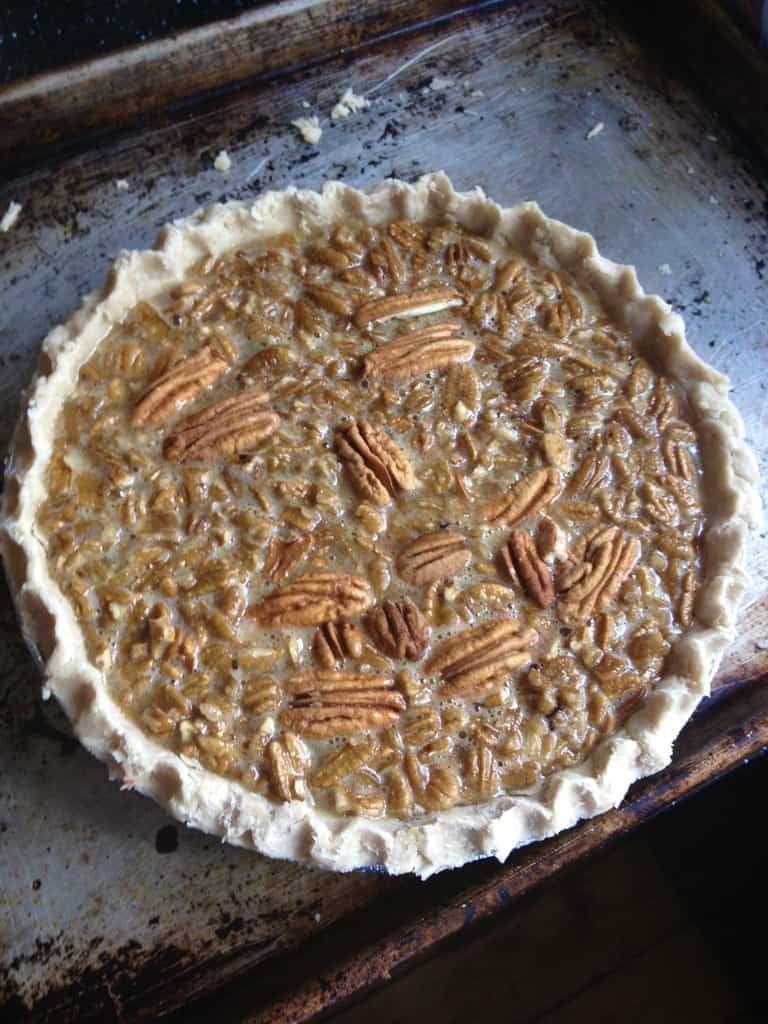 pecan pie with a face made out of the nuts just before being baked