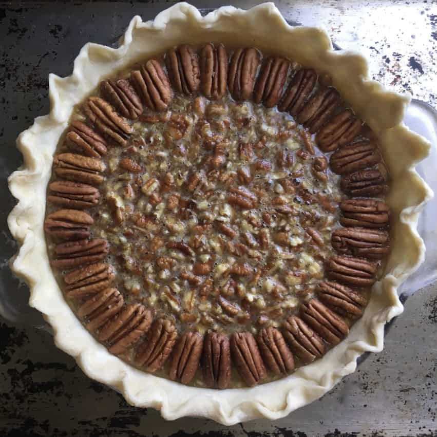 unbaked assembled pecan pie in a glass pyrex pie plate