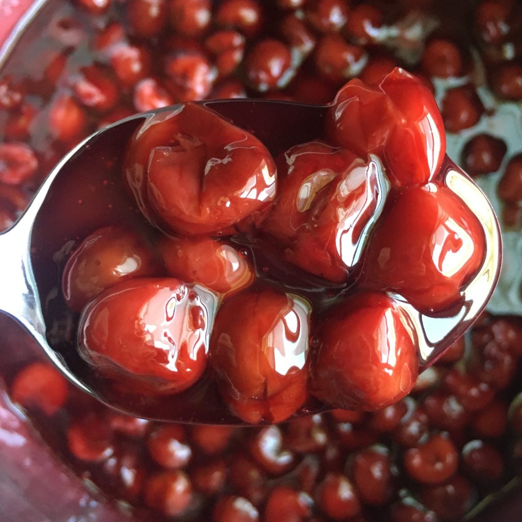 Closeup of homemade cherry pie filling on a spoon.