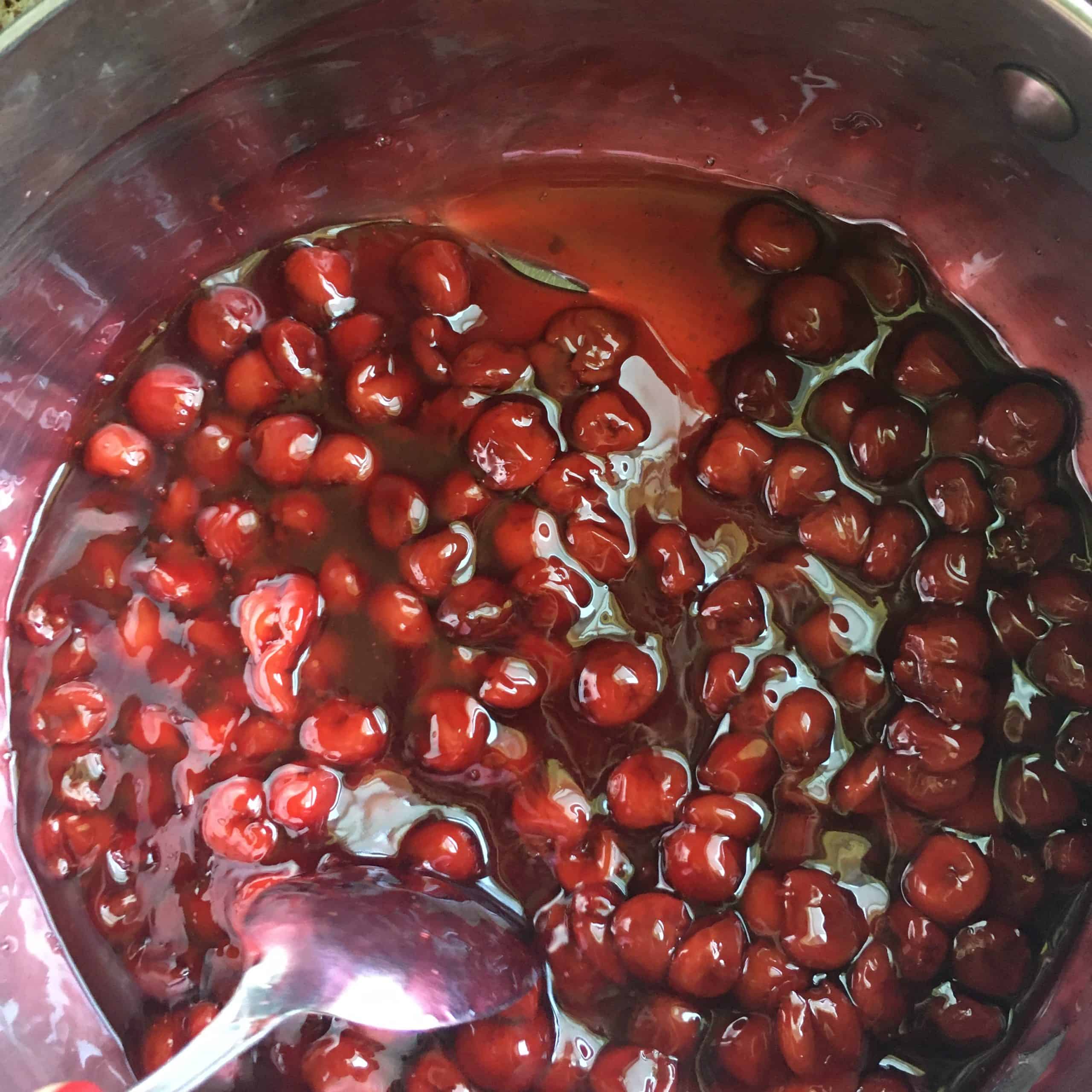 a pot of cherry pie filling with a silver spoon resting in the pot