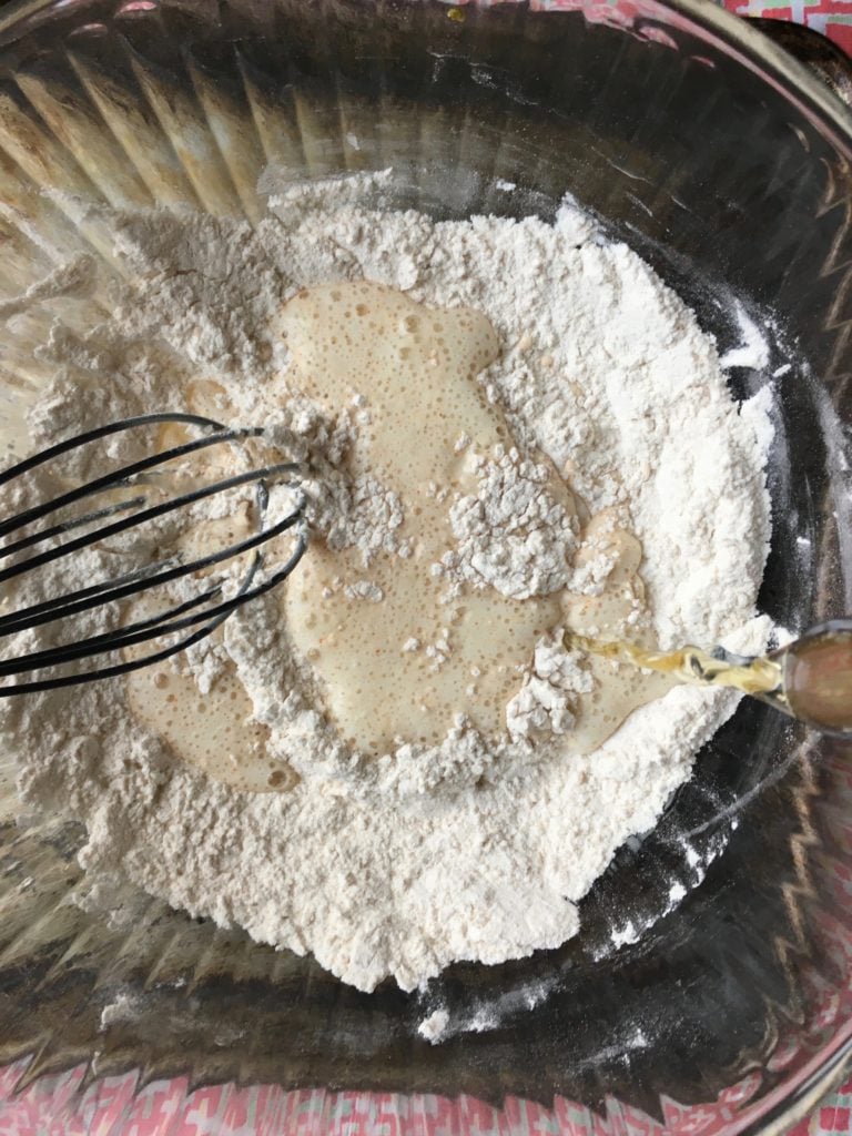 A whisk in a bowl with fish and chips batter not fully blended yet.
