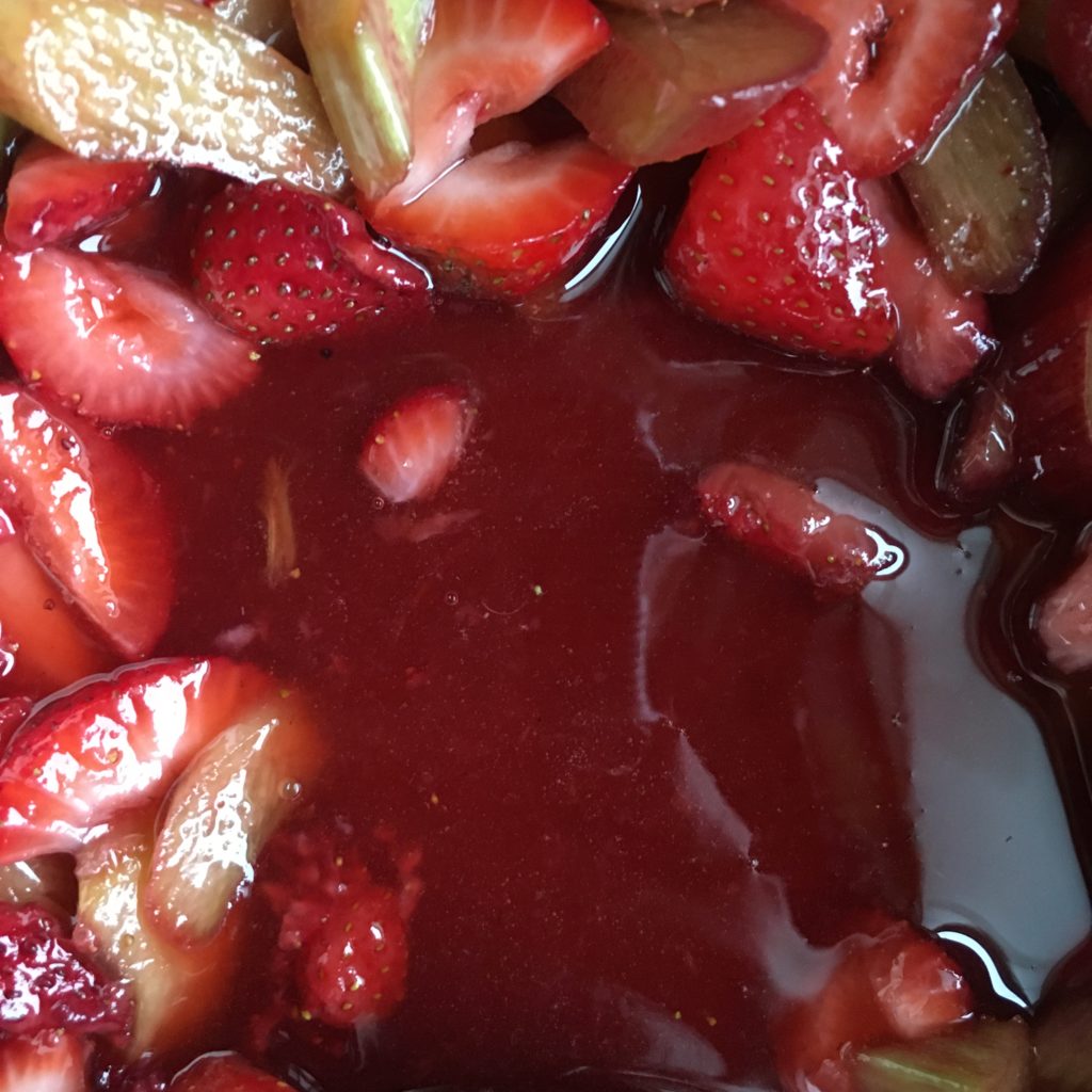 A puddle of juice from strawberry rhubarb mixture cooking and releasing natural juices.