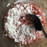 closeup stawberry rhubarb juice with cornstarch added being mixed together with a spoon
