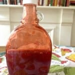 A repurposed maple syrup jar with homemade strawberry coulis in it made with fresh for a professional touch to homemade desserts.