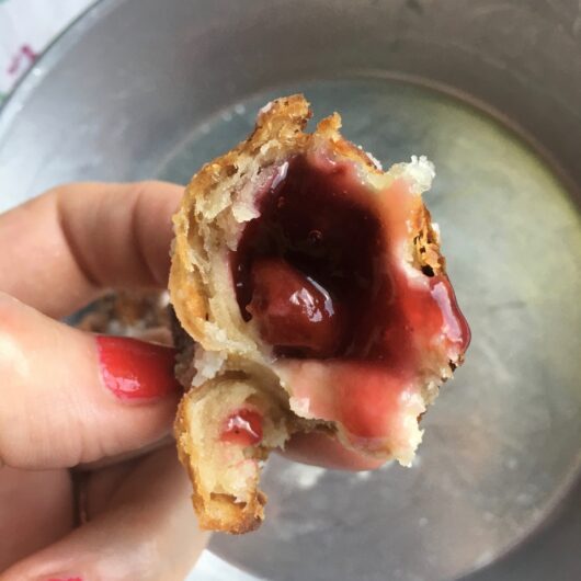 fried pie with a bite taken out and a single cherry inside surrounded by the pie filling