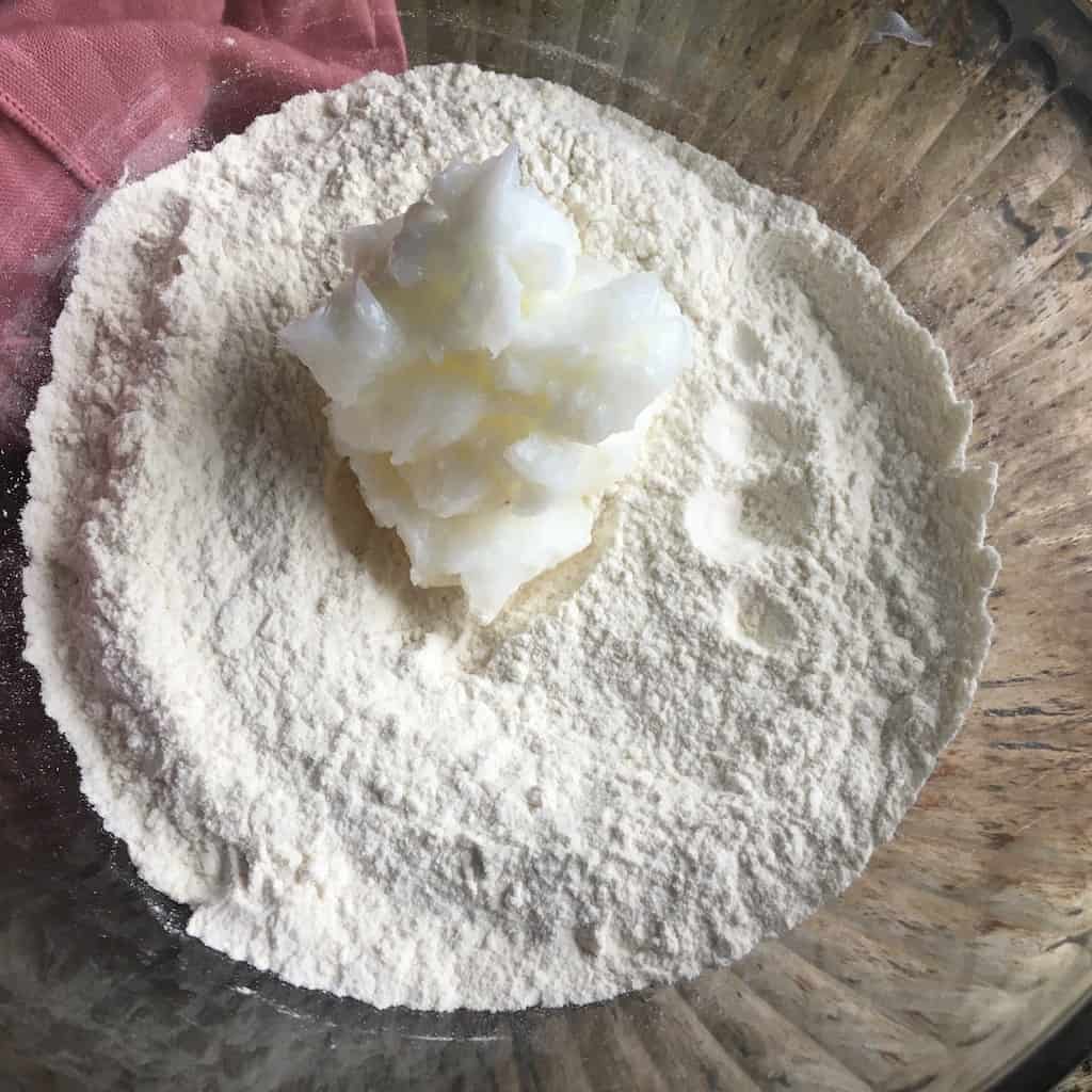 closeup glass mixing bowl with fried pie ingredients in it and a pink napkin lying next to it on the left on top of a sheet pan