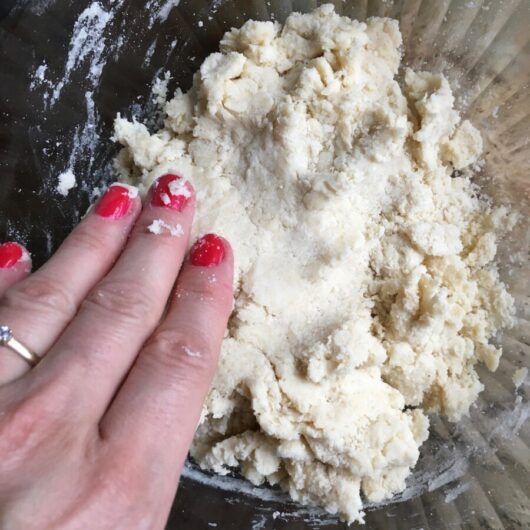 hand patting down the fried pie dough with red nail polish
