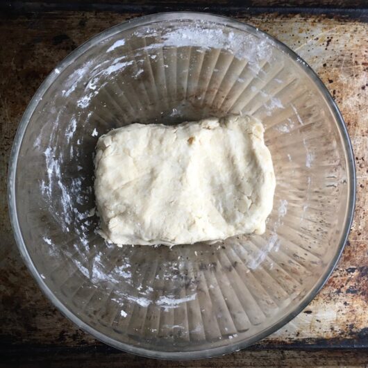 fried pie dough in the shape of a rectangle inside a glass mixing bowl on top of a sheet tray
