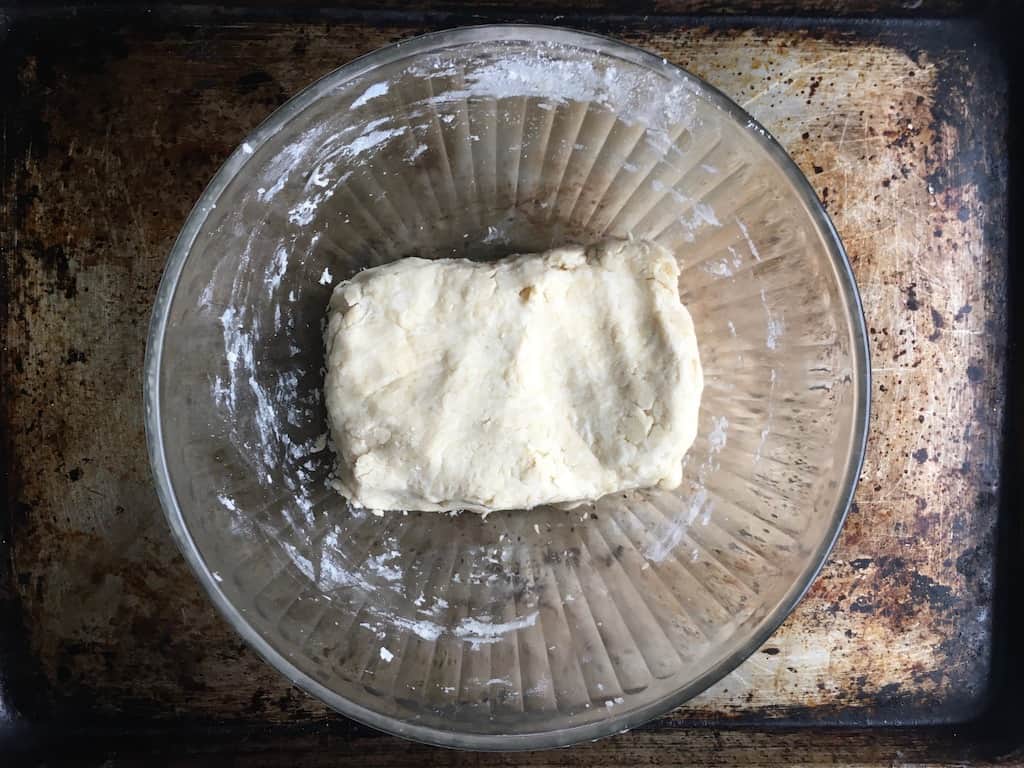 fried pie dough in the shape of a rectangle inside a glass mixing bowl on top of a sheet tray
