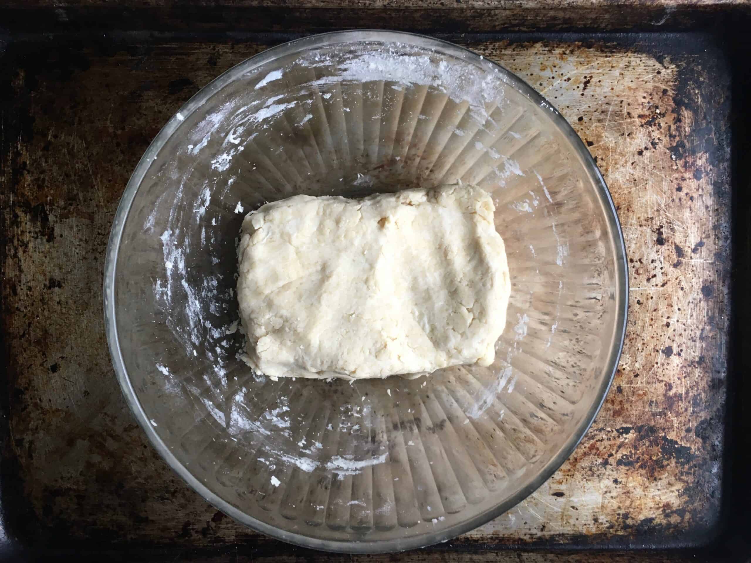 dough brick inside a glass pyrex bowl resting on top of a well-seasoned sheet tray