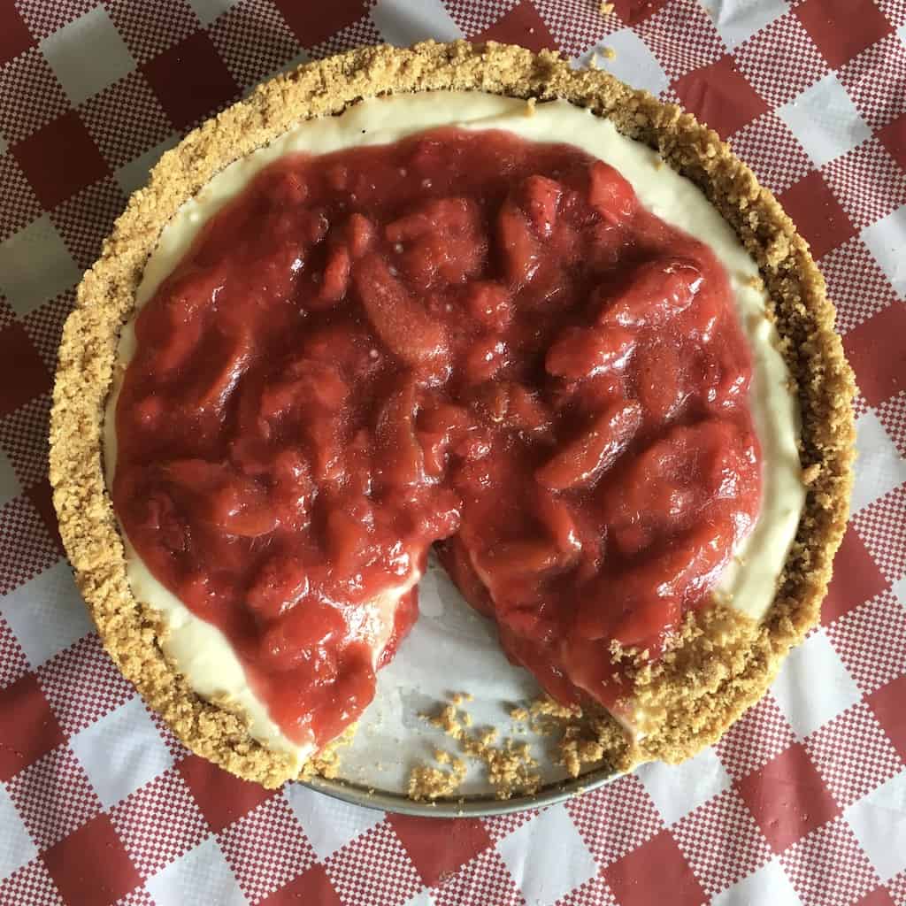 strawberry-rhubarb cream cheese pie on red and white checkered table cloth on a picnic table