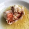 a tender cooked and slightly curled fresh lobster tail sitting in a pasta bowl of clarified butter