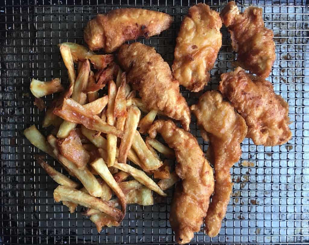 crispy fried chicken tenders and fries on a cooling rack