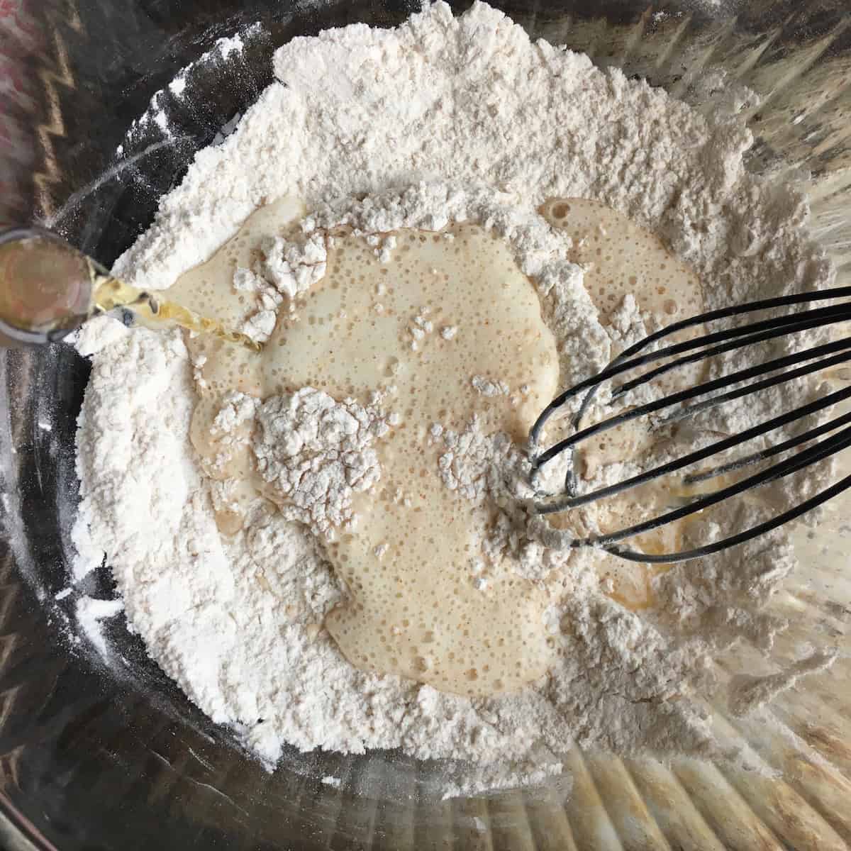 Adding beer to flour mixture to make beer batter for extra crispy fried chicken tenders showing how to make chicken tenders step by step.

