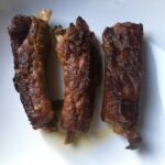 three perfectly cooked fork-tender ribs on a plate