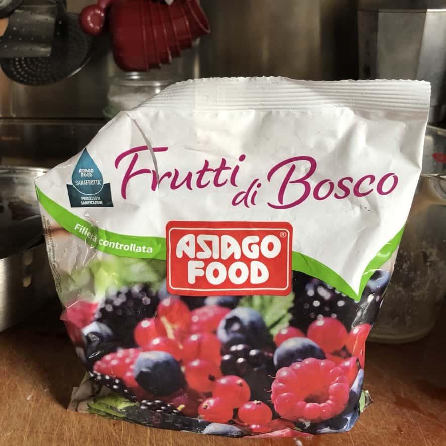 bag of organic frutti di bosco frozen fruit next to a bowl of mixed dry muffin ingredients