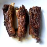 three perfectly cooked fork-tender ribs on a plate