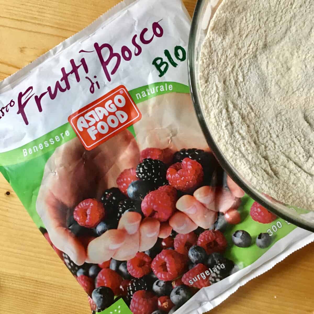bag of organic frutti di bosco frozen fruit next to a bowl of mixed dry muffin ingredients