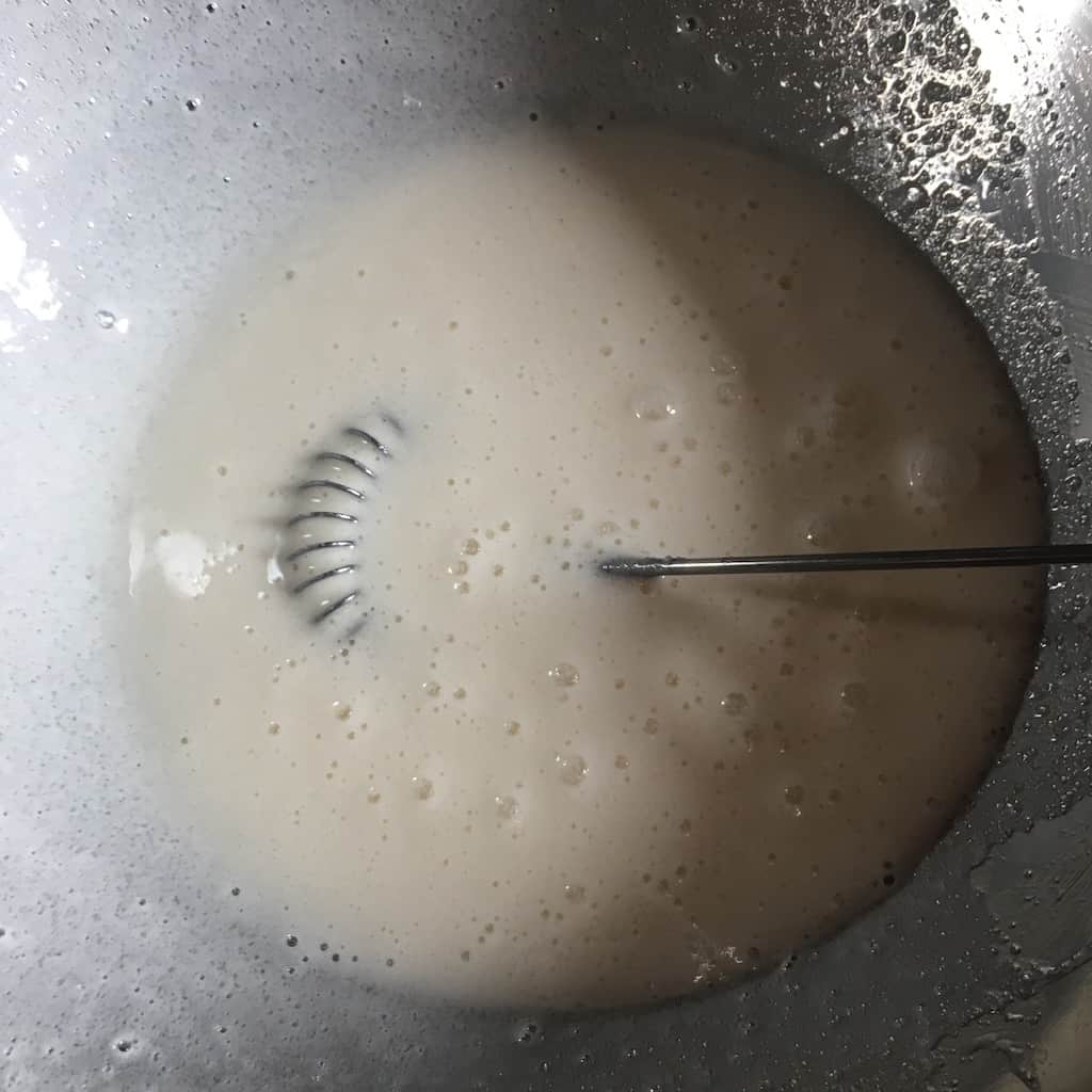 7-minute frosting ingredients in stainless steel bowl with whisk.