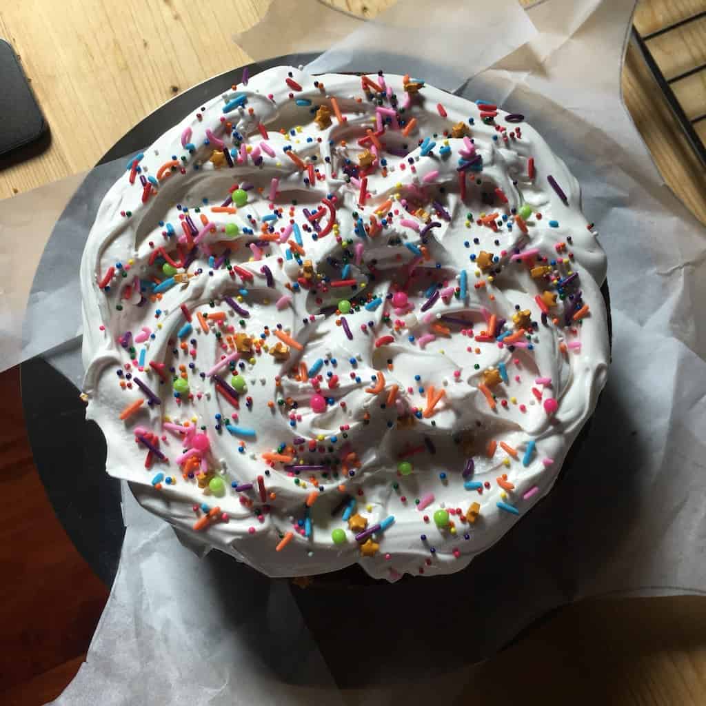 Homemade frosted devil's food cake with sprinkles on top.