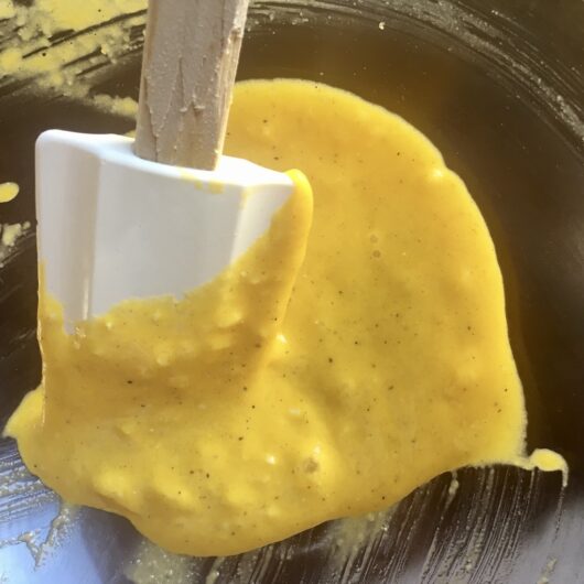 very smooth and bright yellow mixture with white spatula used to stir it still in the mixing bowl