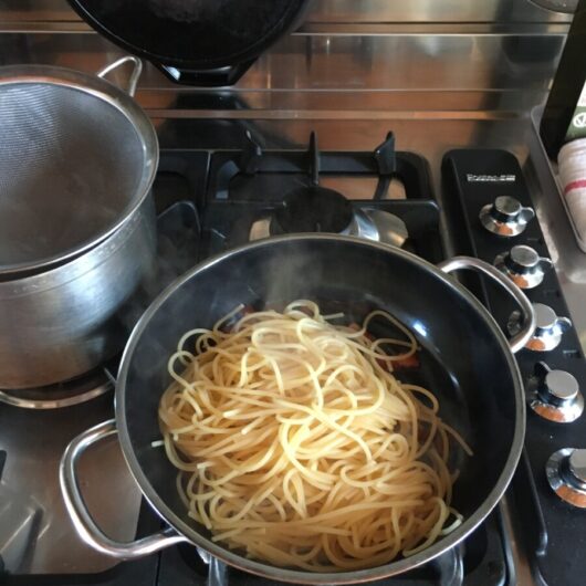 pasta noodles in the skillet with the pancetta