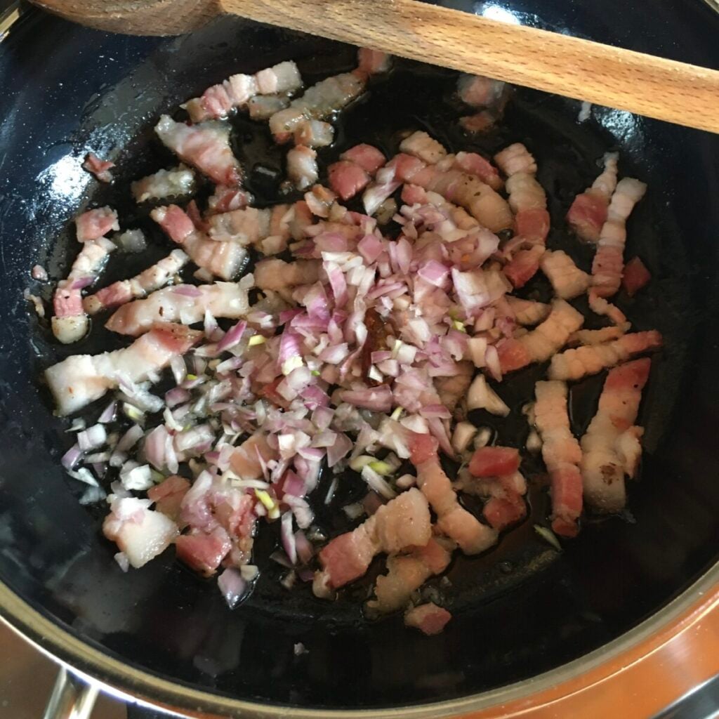 Adding shallots to pancetta and chili pepper for amatriciana