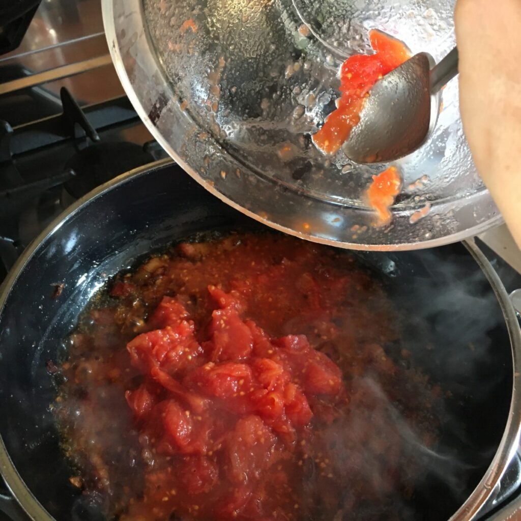 Adding fresh tomatoes to the amatriciana sauce
