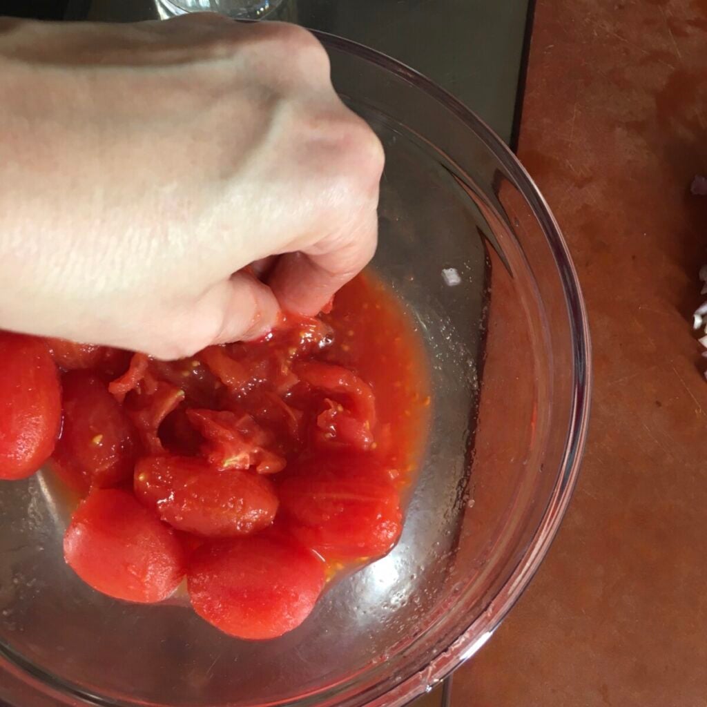 Crushing peeled tomatoes by hand for amatriciana