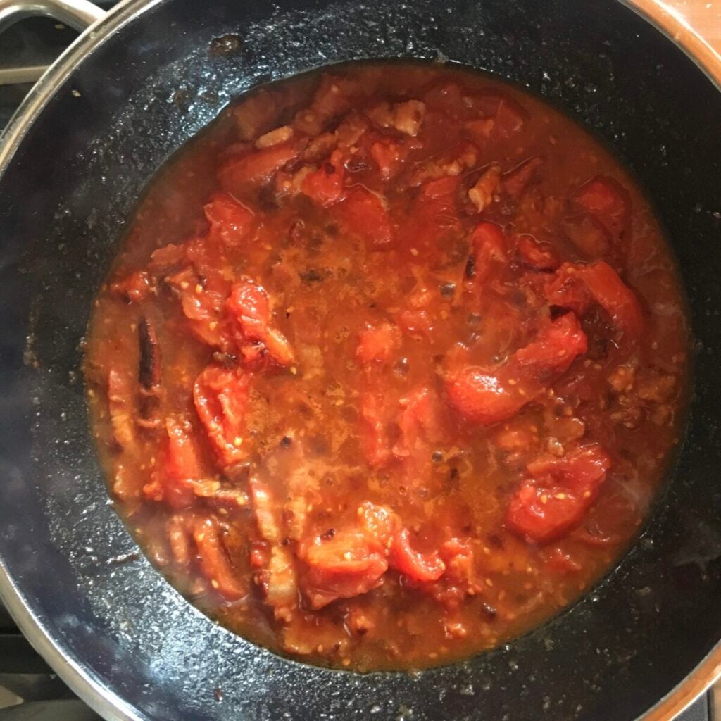 Reducing tomatoes in the amatriciana sauce