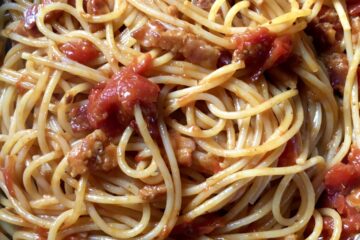 a top down view of delicious spaghetti all amatriciana in a navy blue braising pan