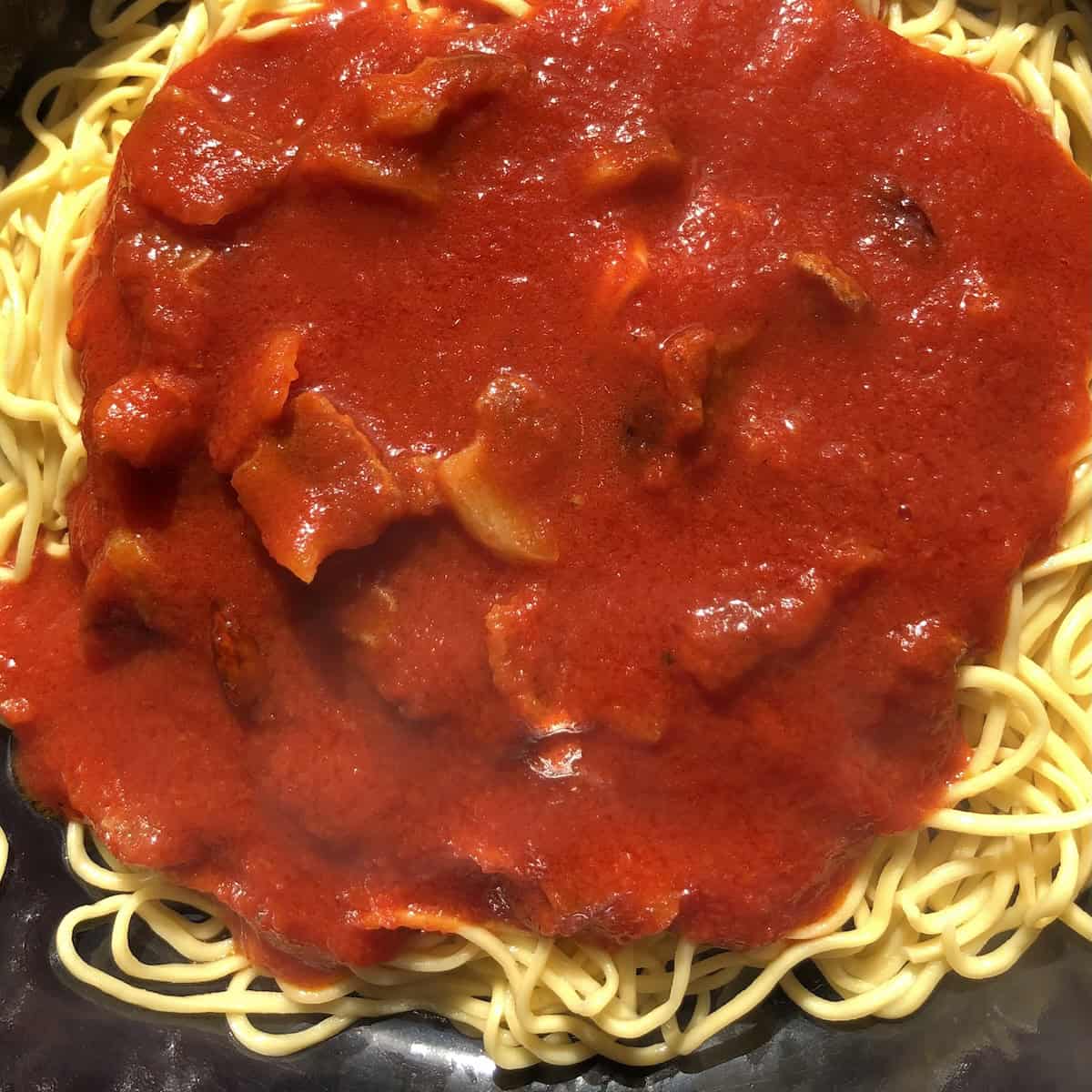 Amatriciana sauce added on top of strained homemade pasta before stirring, pasta amatriciana recipe final steps.