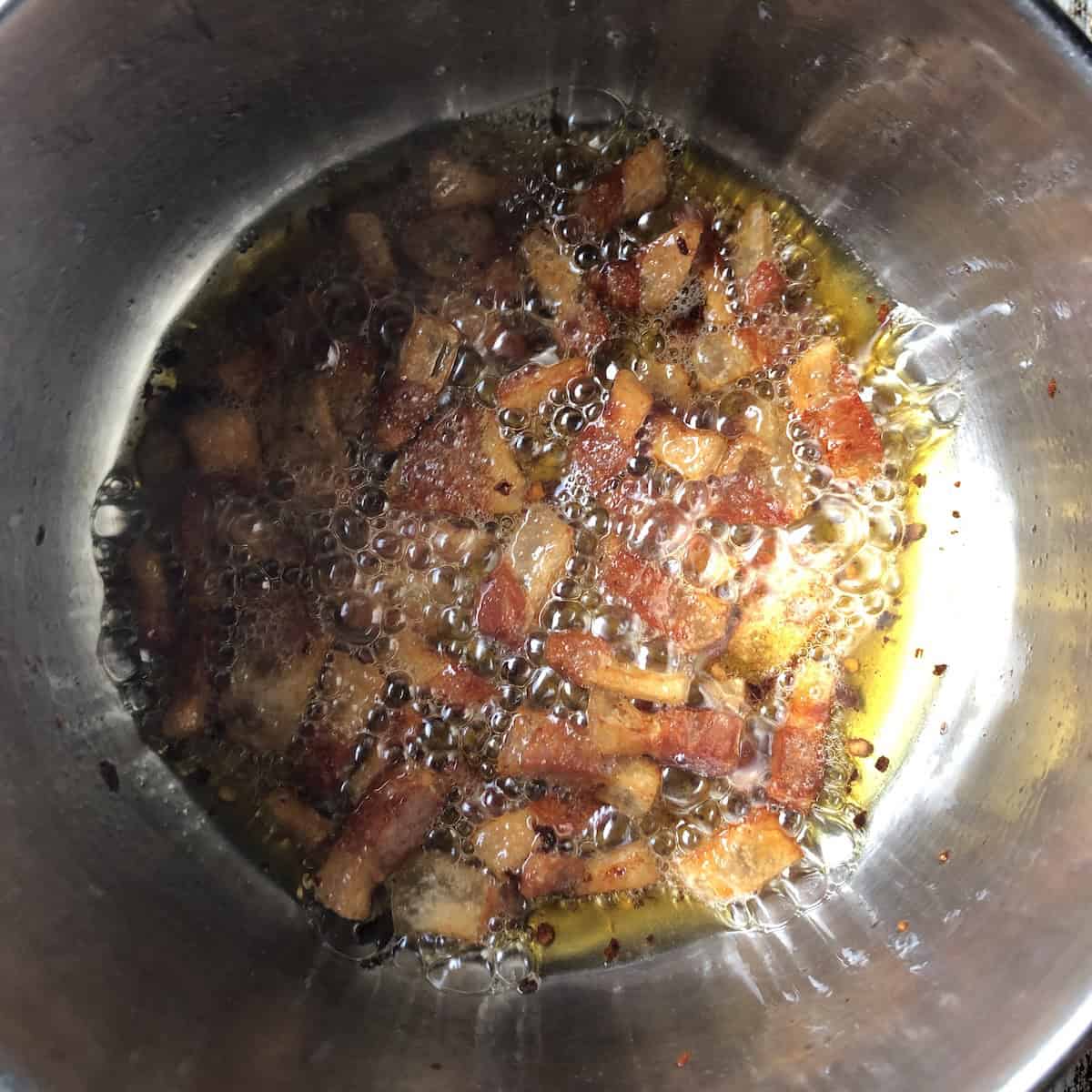 Pot of perfectly cooked guanciale ready to deglaze with white wine for amatriciana sauce recipe.
