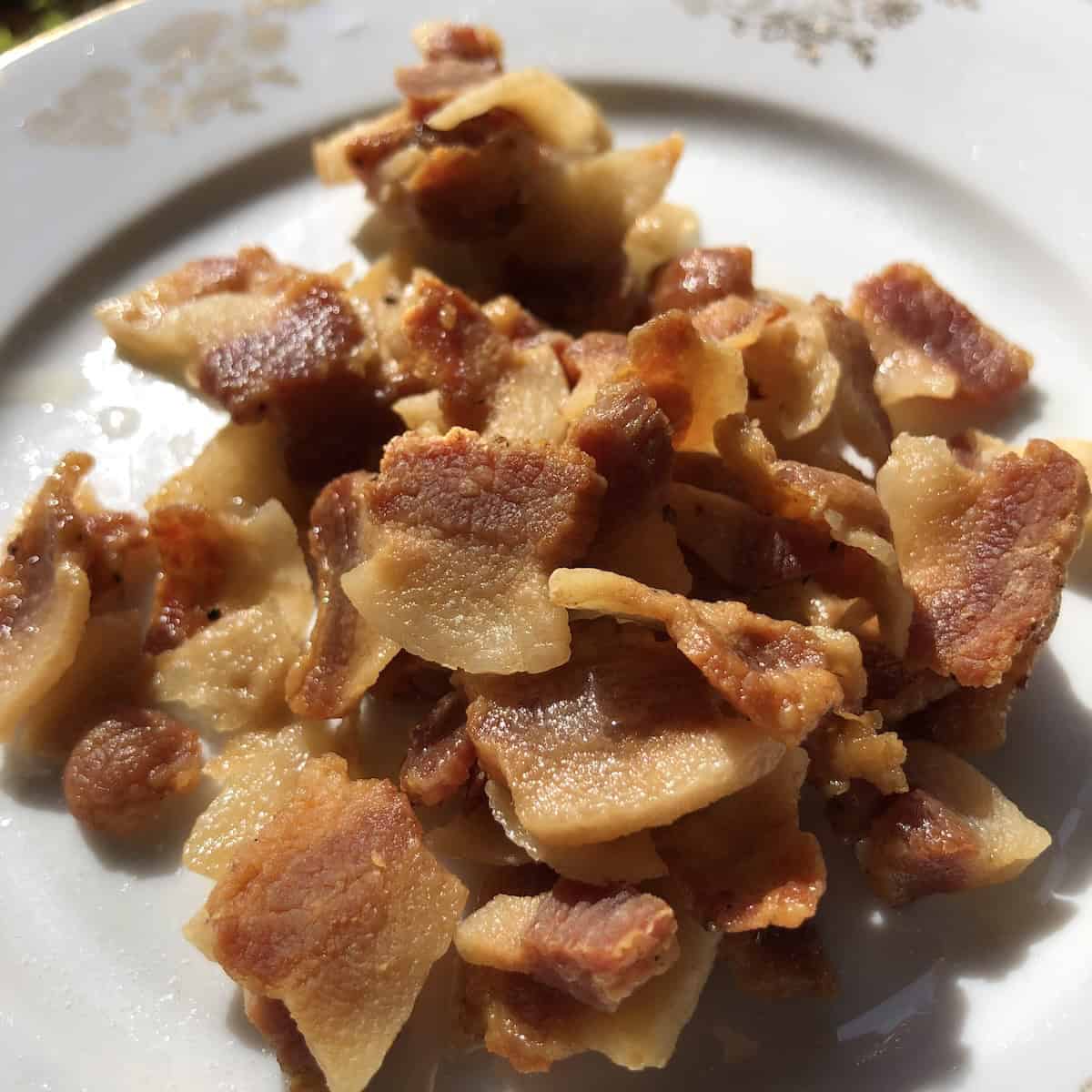Crispy cooked guanciale slices ready for amatriciana, carbonara, or gricia pasta, showing how to slice and cook Italian cured pork jowl.
