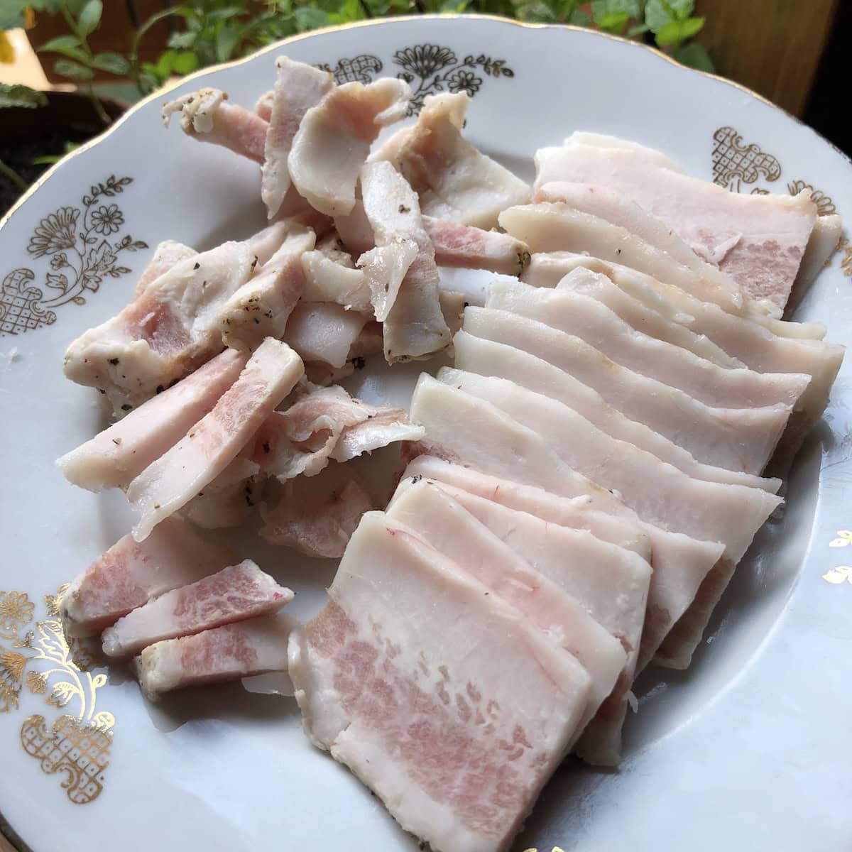 Sliced guanciale next to matchstick cuts on plate showing how to cut cured pork jowl for crispy and tender pieces in amatriciana, gricia, or carbonara pasta.
