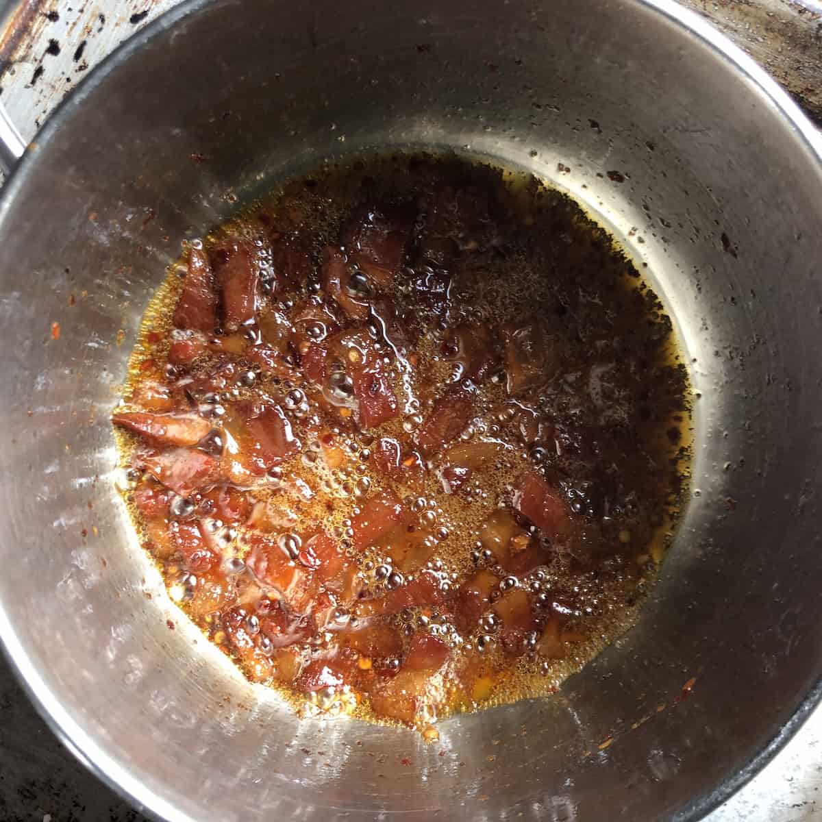 Glossy guanciale after wine has evaporated ready for tomatoes, authentic amatriciana sauce recipe preparation.