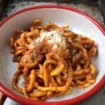 Finished homemade bucatini all'amatriciana topped with grated pecorino cheese and freshly cracked black pepper, authentic pasta amatriciana recipe.