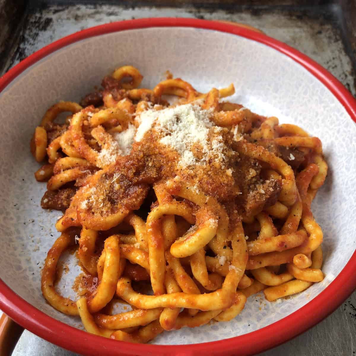 Finished homemade bucatini all'amatriciana topped with grated pecorino cheese and freshly cracked black pepper, authentic pasta amatriciana recipe.
