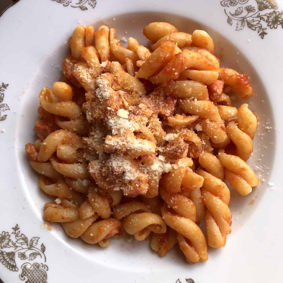 Pasta all'amatriciana with Rustichella d'Abruzzo gran fusilli in bowl sprinkled with pecorino cheese, authentic amatriciana recipe ready to serve.