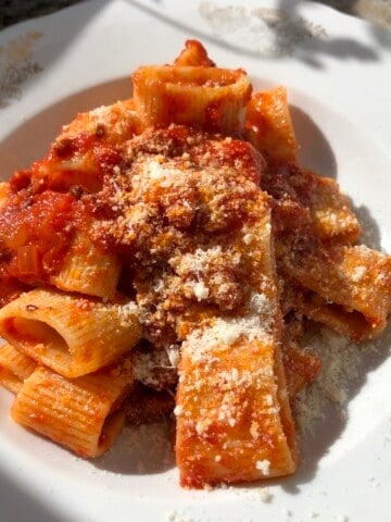 Rustichella d'Abruzzo manconi pasta all'amatriciana sprinkled with pecorino romano, authentic Italian amatriciana pasta recipe.