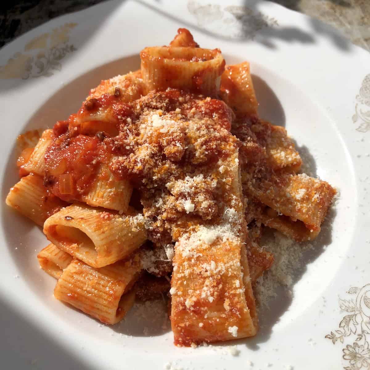 Rustichella d'Abruzzo manconi pasta all'amatriciana sprinkled with pecorino romano, authentic Italian amatriciana pasta recipe.
