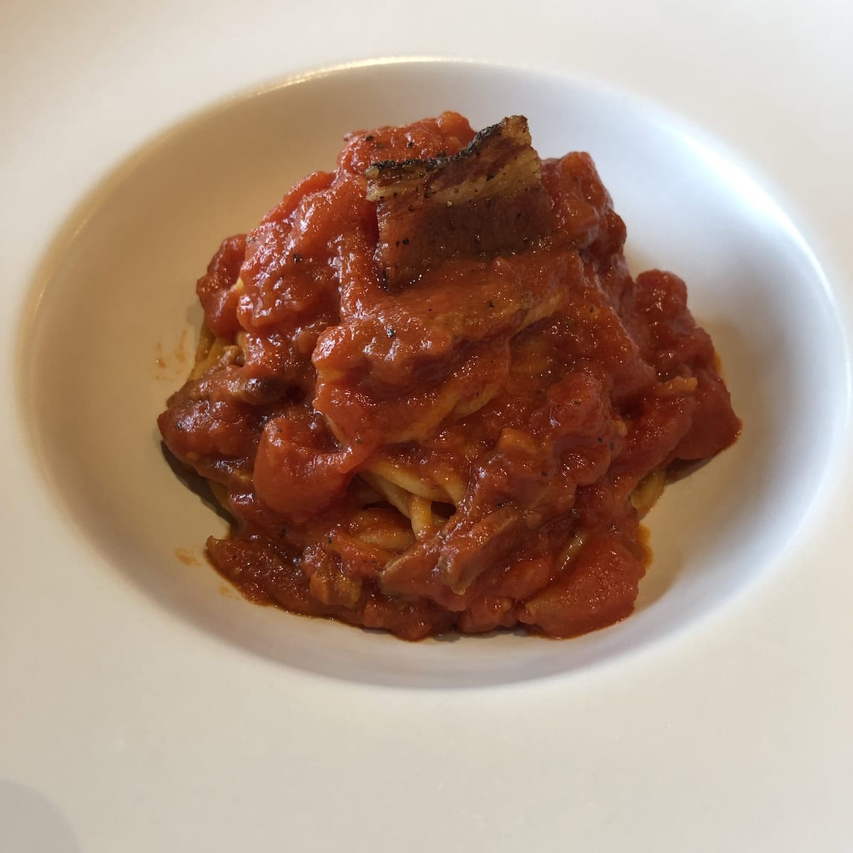 Spaghetti alla chitarra amatriciana from Frekt restaurant in Verona Italy, traditional abruzzese pasta with authentic amatriciana sauce and guanciale and covered in too much tomato sauce.