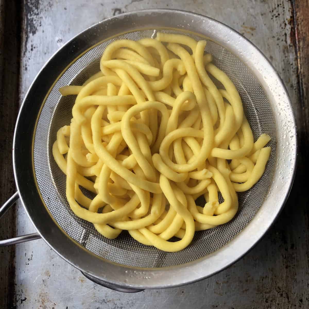 Strained homemade bucatini pasta ready to add to amatriciana sauce for bucatini all'amatriciana recipe.
