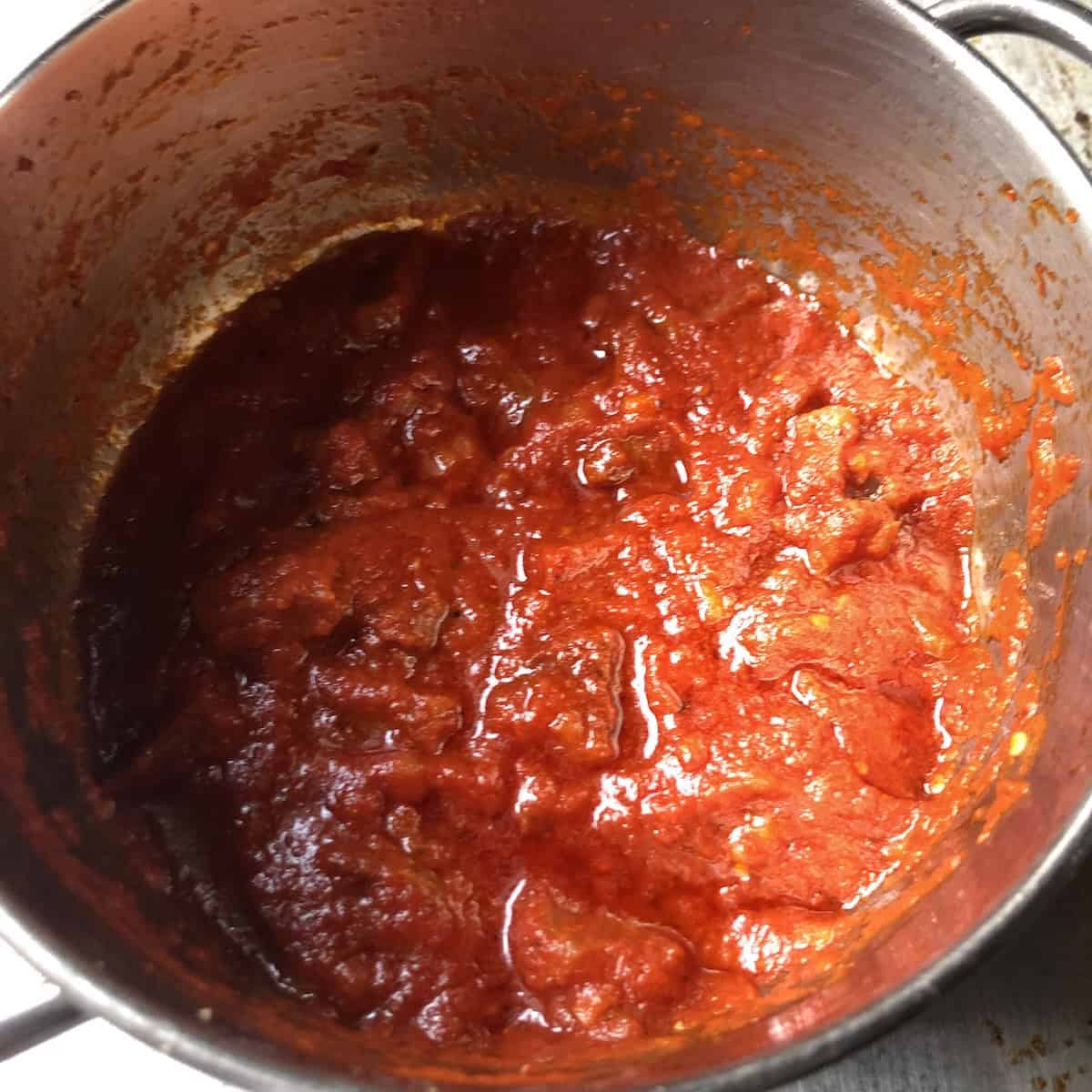 Tomatoes added to guanciale simmering in pot, how to make authentic amatriciana sauce recipe.
