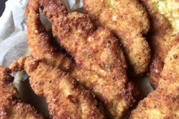 basil parm panko crusted chicken cooked to golden brown stacked on a platter with a view out of the window