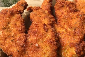 basil parm panko crusted chicken cooked to golden brown stacked on a platter with a view out of the window