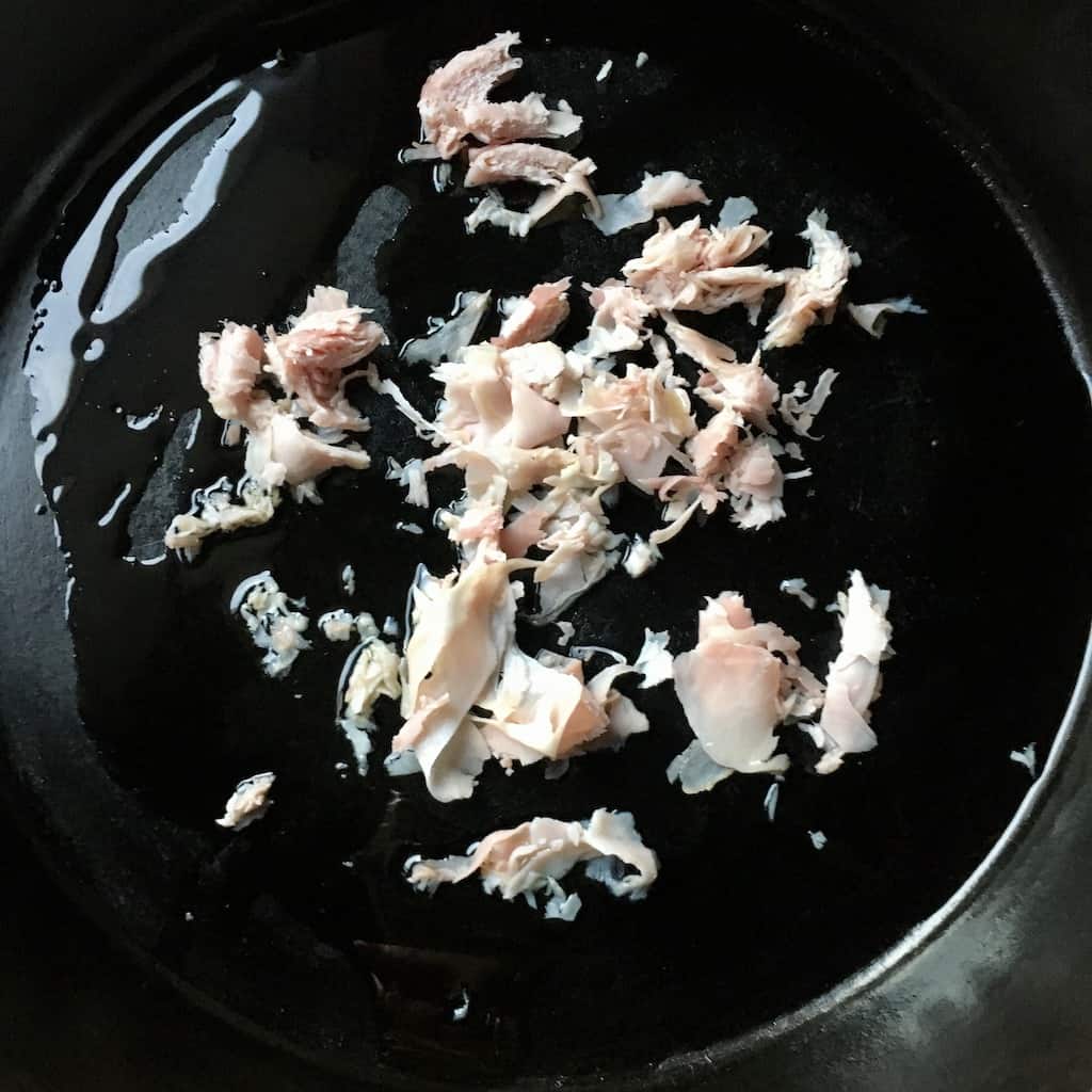 prosciutto cotto cooking in olive oil in a cast iron skillet